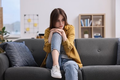 Loneliness concept. Sad teenage girl on sofa at home