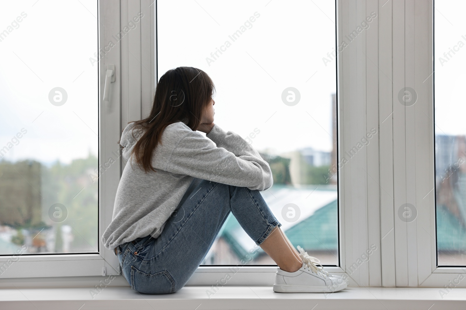 Photo of Loneliness concept. Sad teenage girl on windowsill at home