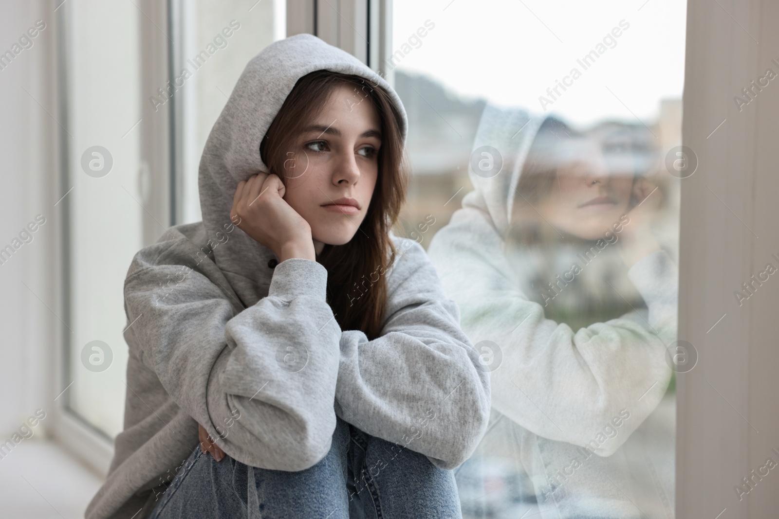 Photo of Loneliness concept. Sad teenage girl near window at home