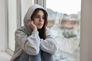 Photo of Loneliness concept. Sad teenage girl near window at home