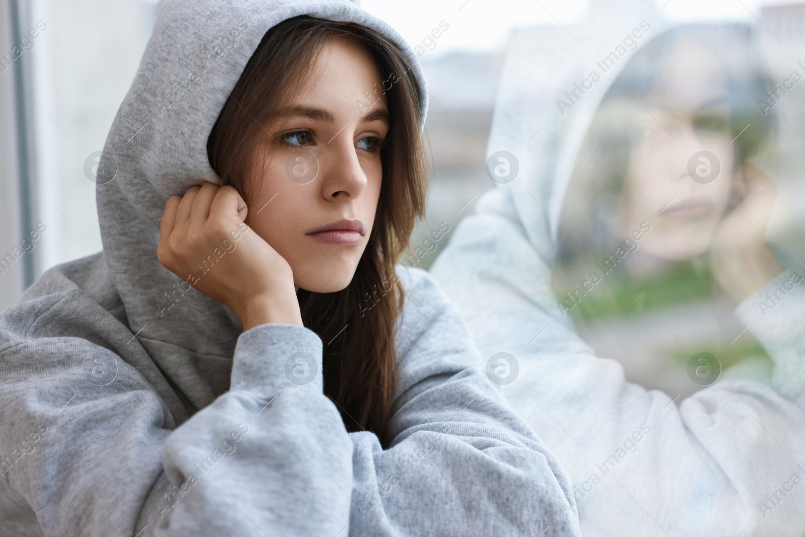 Photo of Loneliness concept. Sad teenage girl near window at home