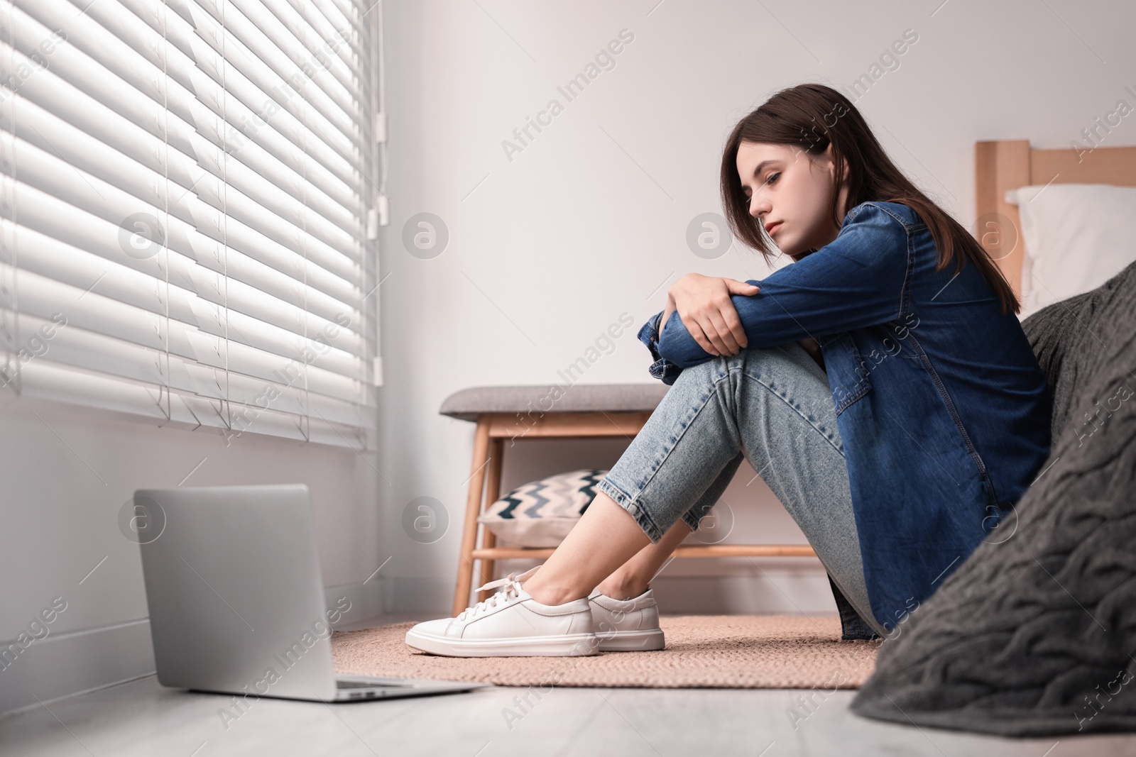 Photo of Loneliness concept. Sad teenage girl with laptop on floor at home