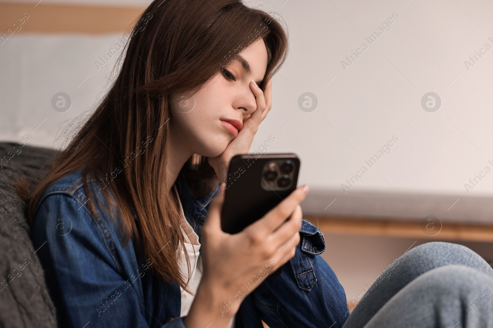 Photo of Loneliness concept. Sad teenage girl with smartphone at home