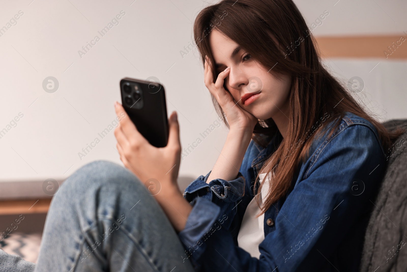 Photo of Loneliness concept. Sad teenage girl with smartphone at home