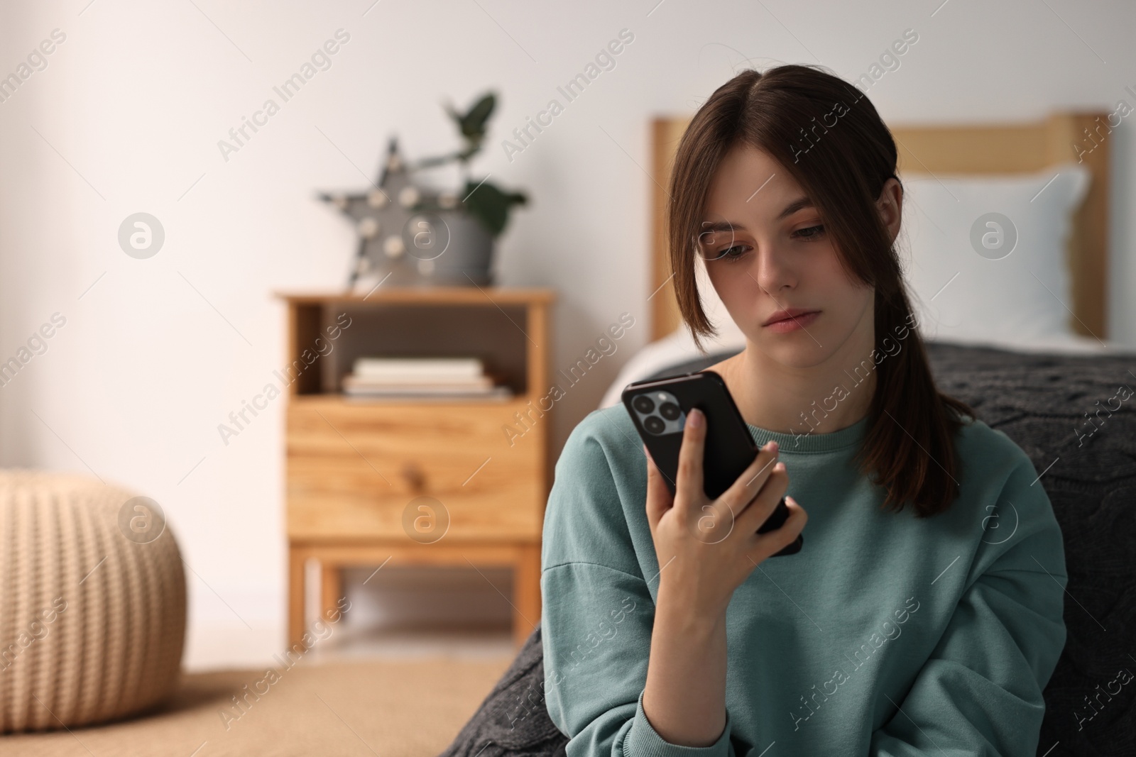 Photo of Loneliness concept. Sad teenage girl using smartphone at home, space for text