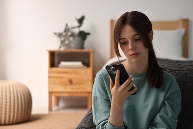 Loneliness concept. Sad teenage girl using smartphone at home, space for text