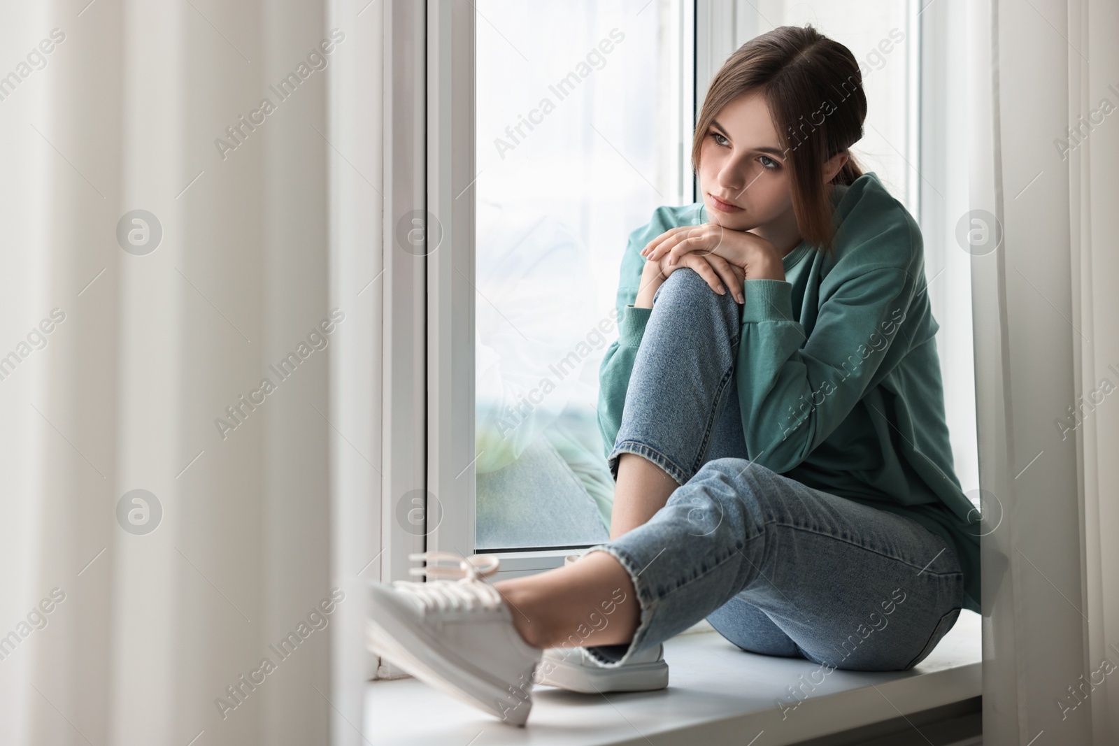 Photo of Loneliness concept. Sad teenage girl on windowsill at home