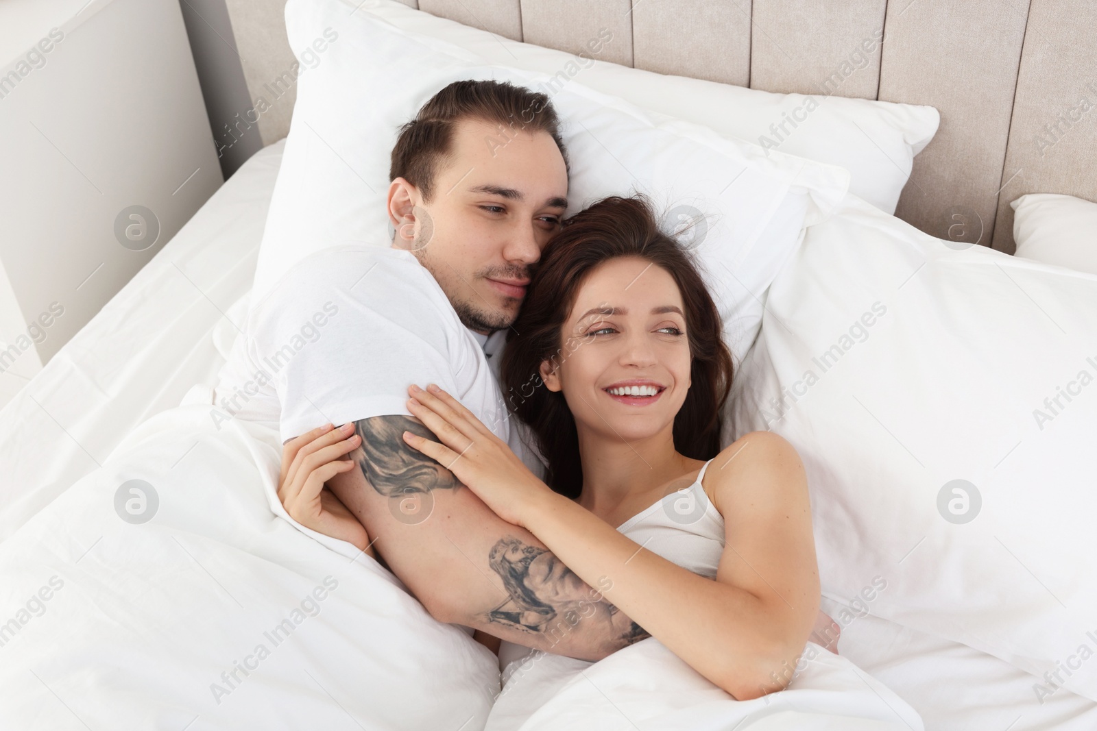 Photo of Happy couple lying in bed at home