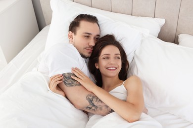 Photo of Happy couple lying in bed at home