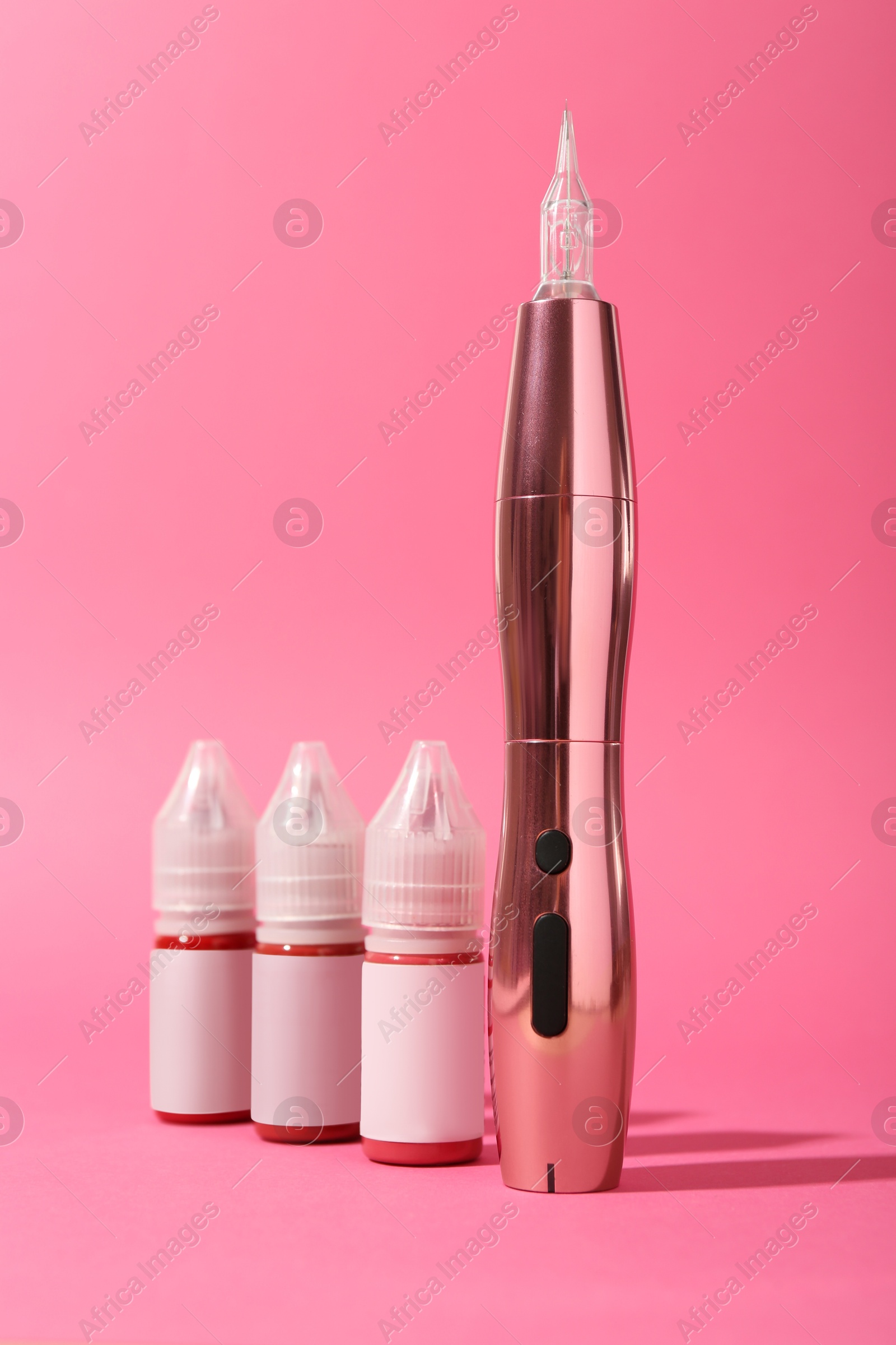 Photo of Permanent makeup machine and pigments on pink background