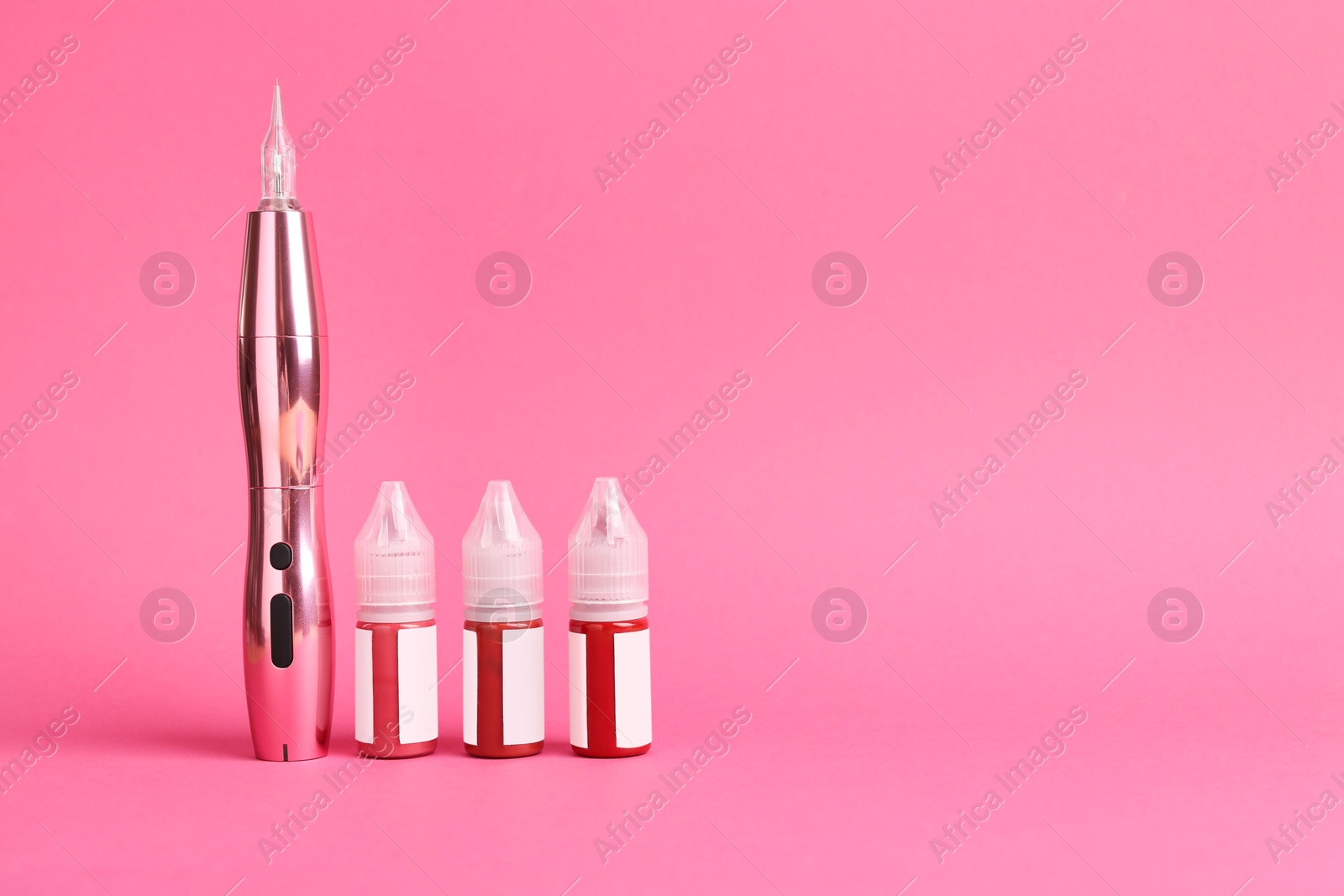 Photo of Permanent makeup machine and pigments on pink background. Space for text