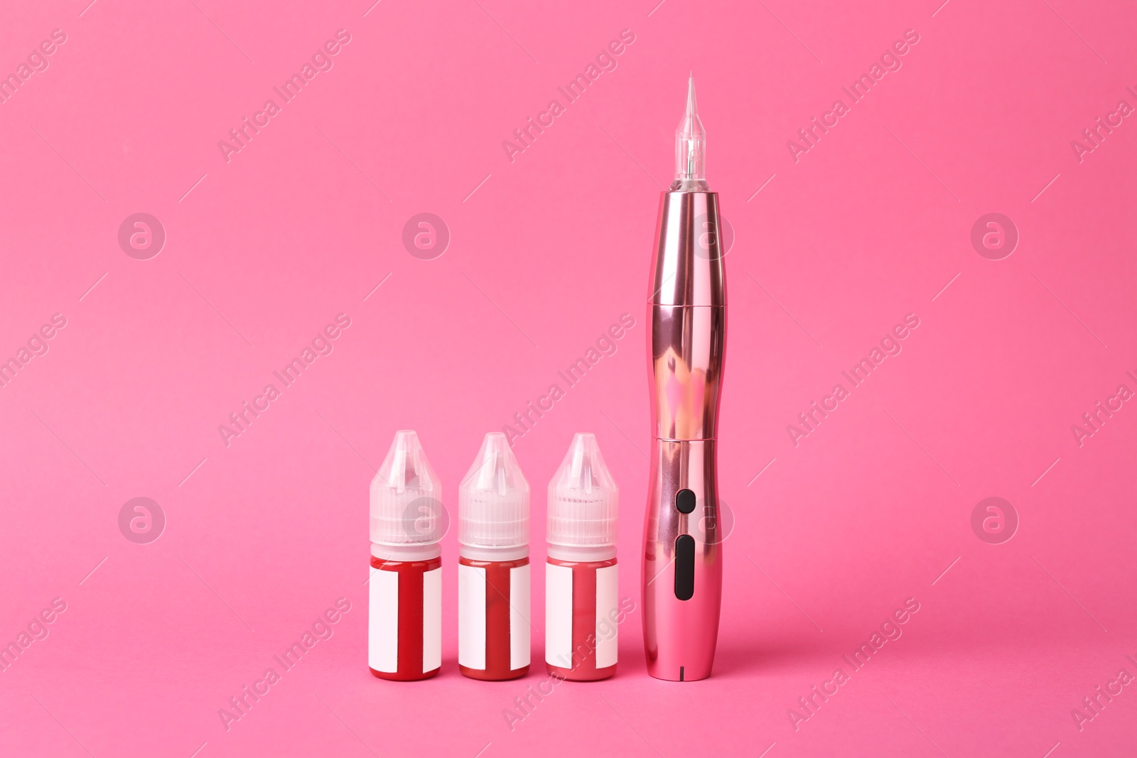 Photo of Permanent makeup machine and pigments on pink background