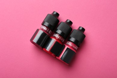 Bottles of pigments for permanent makeup on pink background, top view