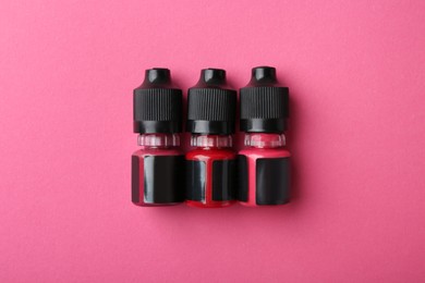 Bottles of pigments for permanent makeup on pink background, top view