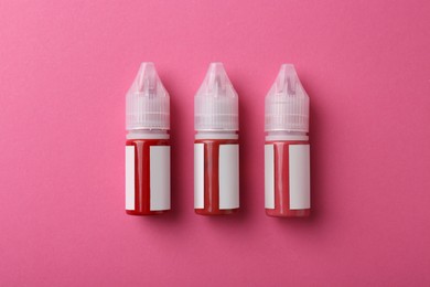 Bottles of pigments for permanent makeup on pink background, top view