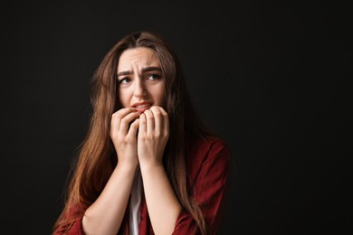 Portrait of scared woman on black background. Space for text