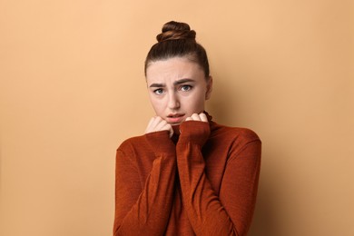 Portrait of scared woman on beige background