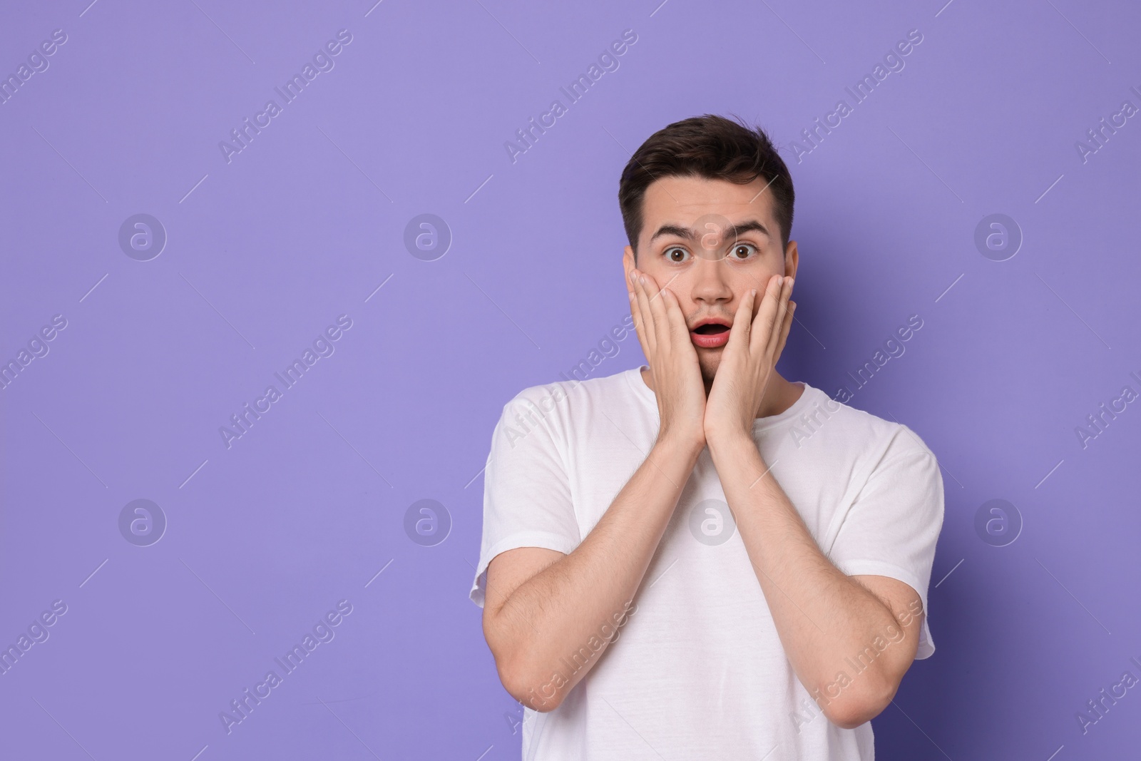 Photo of Portrait of scared young man on violet background, space for text