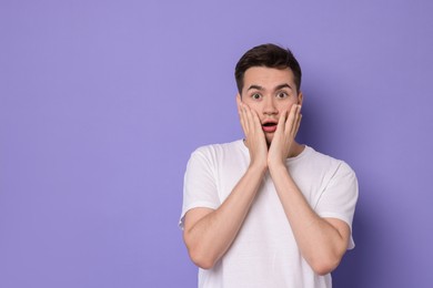 Photo of Portrait of scared young man on violet background, space for text