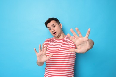 Photo of Portrait of scared young man on light blue background