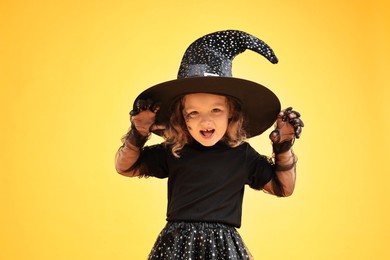 Photo of Funny girl dressed like witch on yellow background. Halloween costume