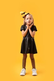 Cute girl dressed like witch on yellow background. Halloween celebration