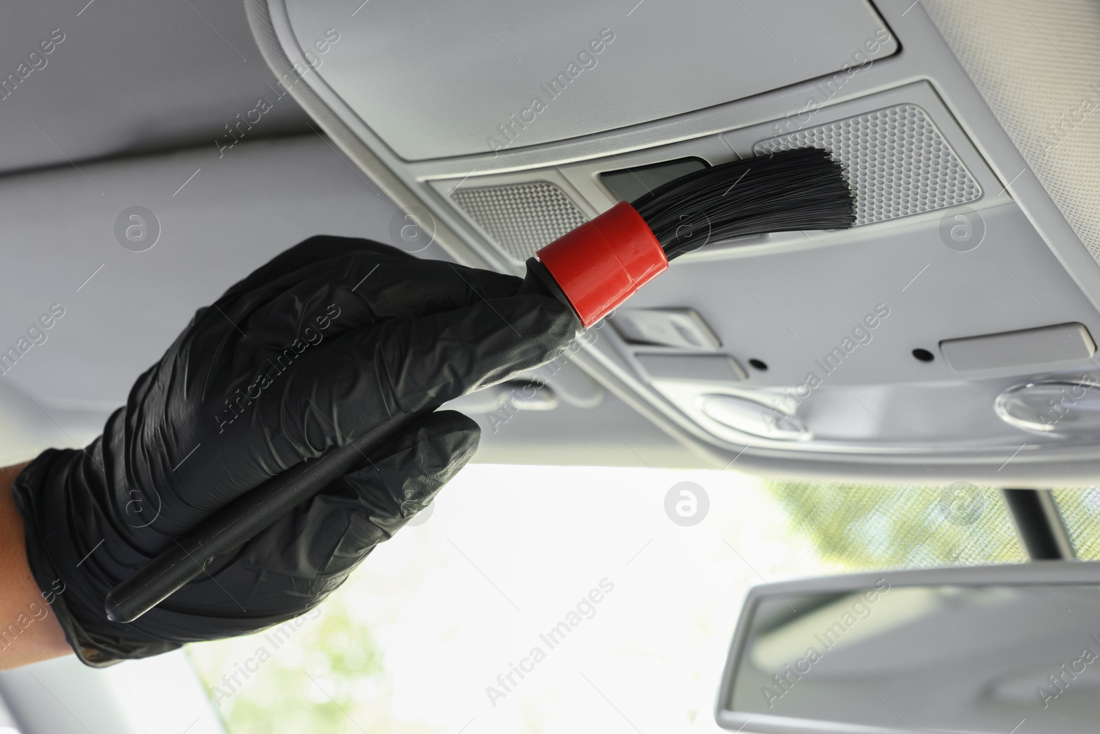 Photo of Man cleaning car interior with brush, closeup