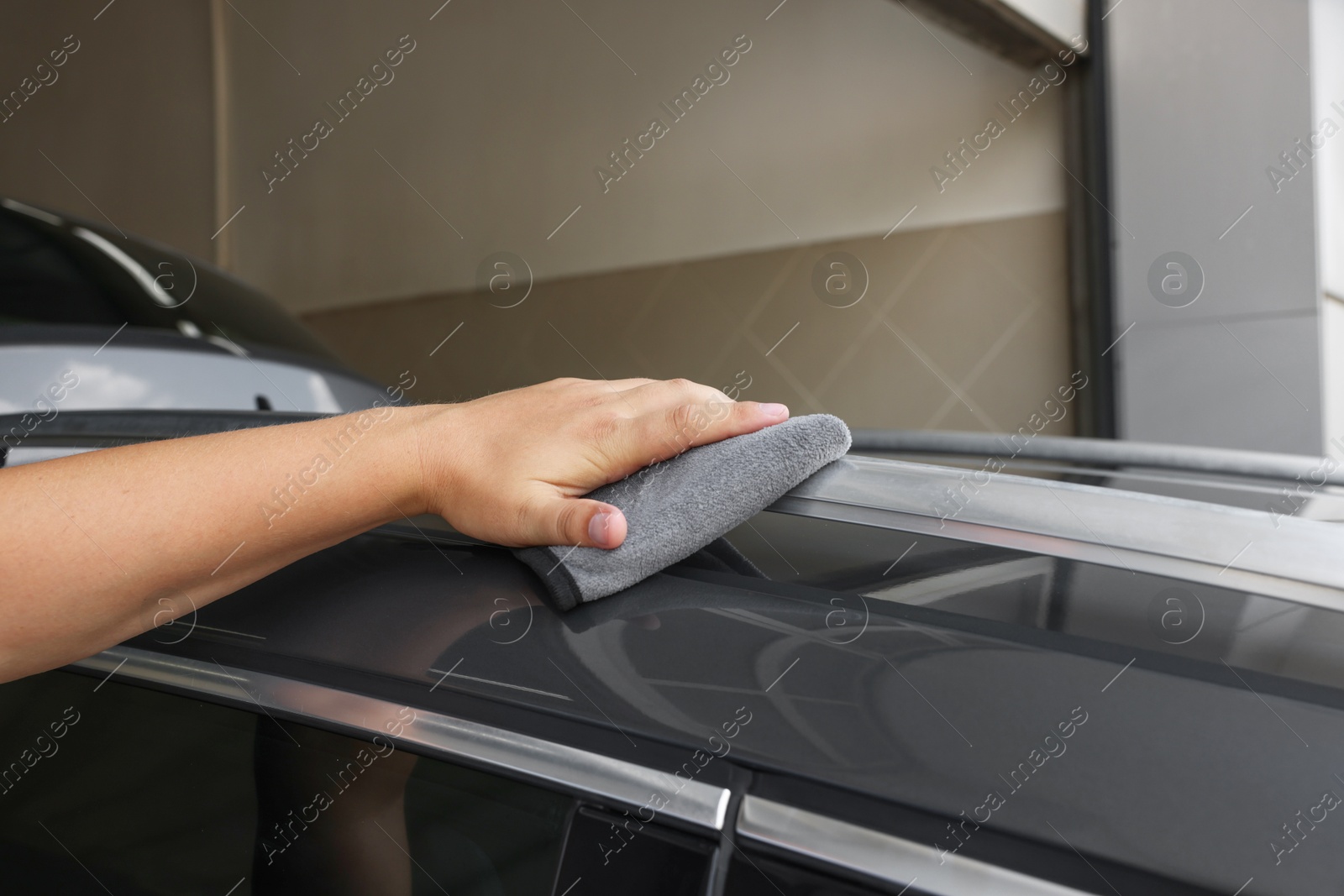 Photo of Man wiping car with grey rag, closeup