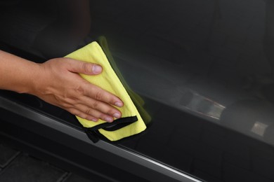 Photo of Man wiping car door with yellow rag, closeup