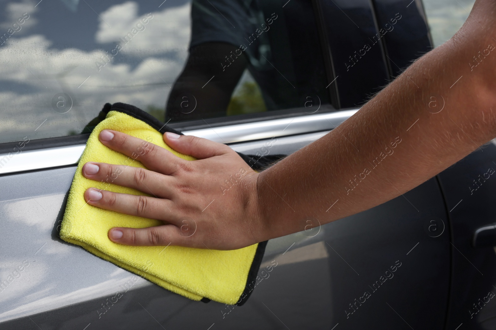 Photo of Man wiping car door with yellow rag, closeup