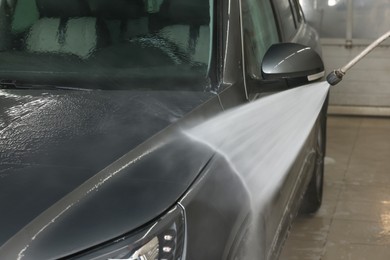 Washing auto with high pressure water jet at car wash, closeup