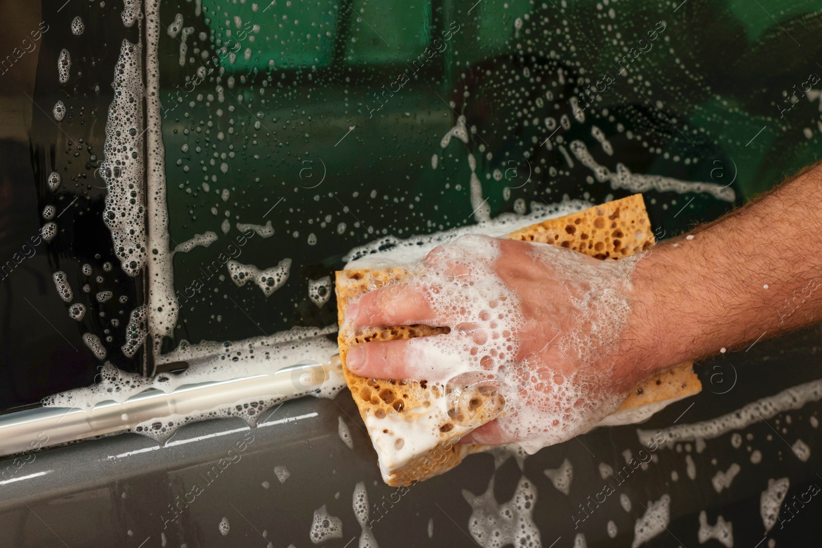 Photo of Man washing auto with sponge at car wash, closeup