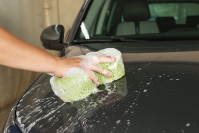 Photo of Man washing car hood with sponge indoors, closeup