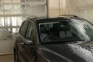 Photo of Washing auto with high pressure water jet at car wash, closeup