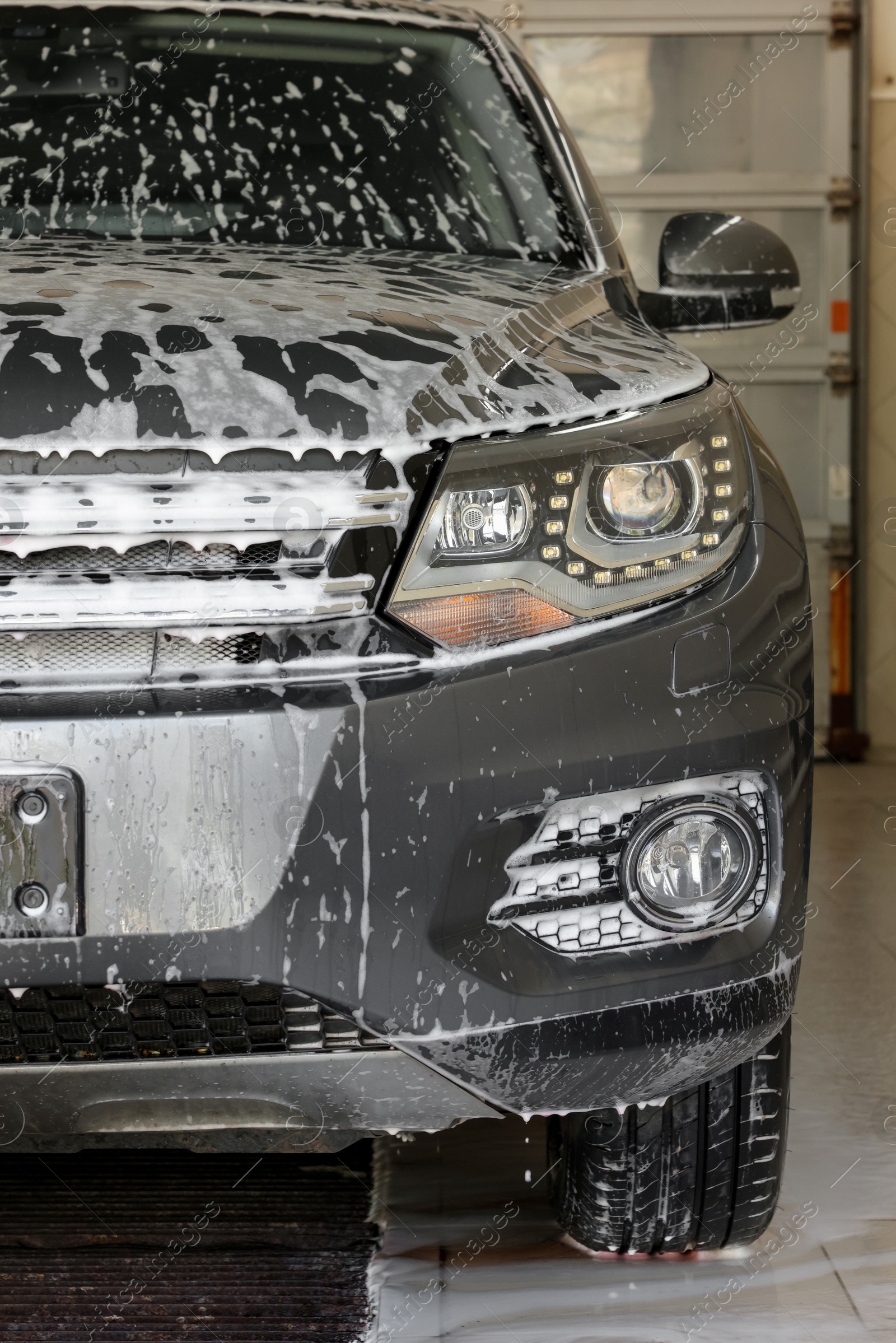 Photo of Auto covered with cleaning foam at car wash, closeup