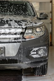 Auto covered with cleaning foam at car wash, closeup