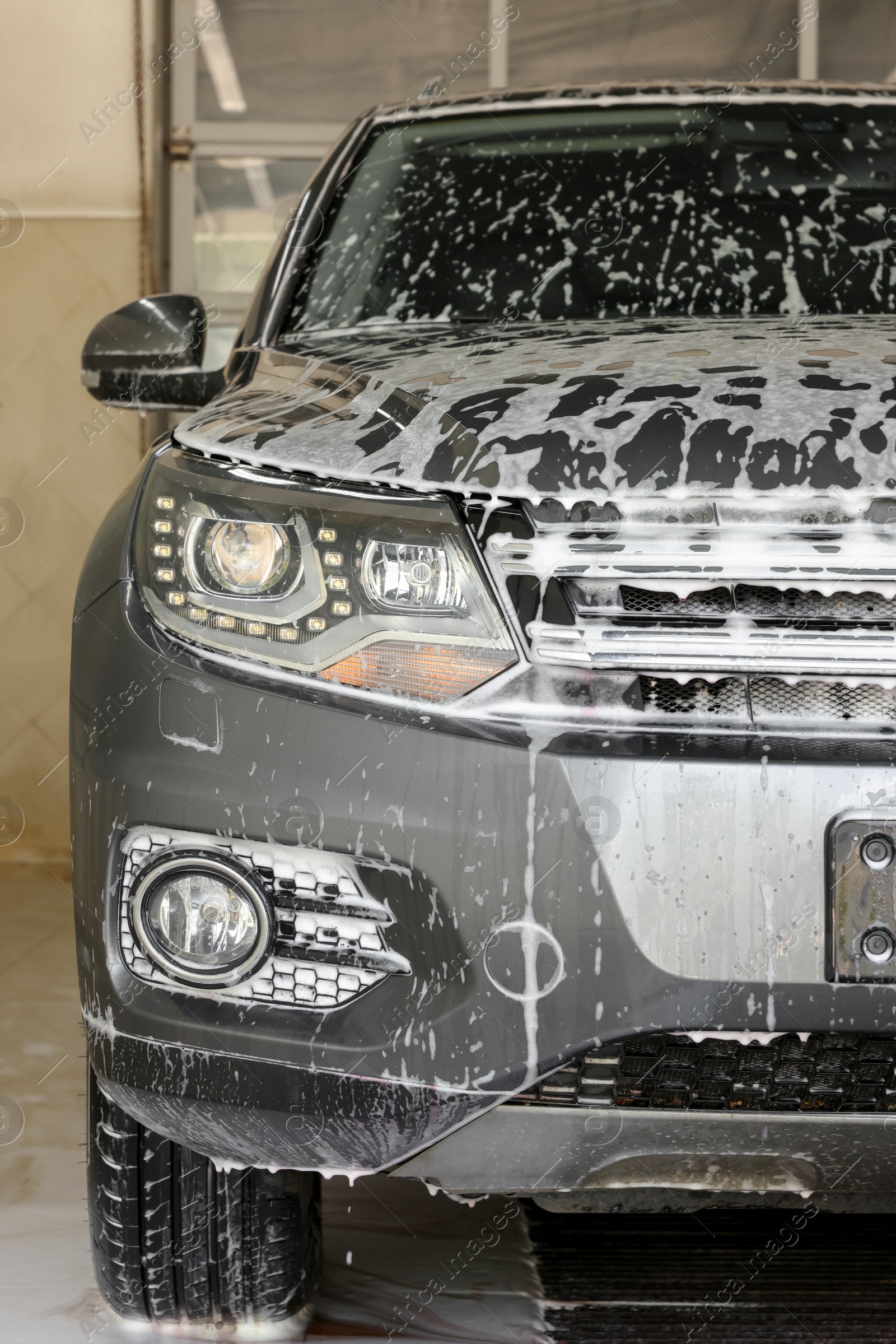 Photo of Auto covered with cleaning foam at car wash, closeup