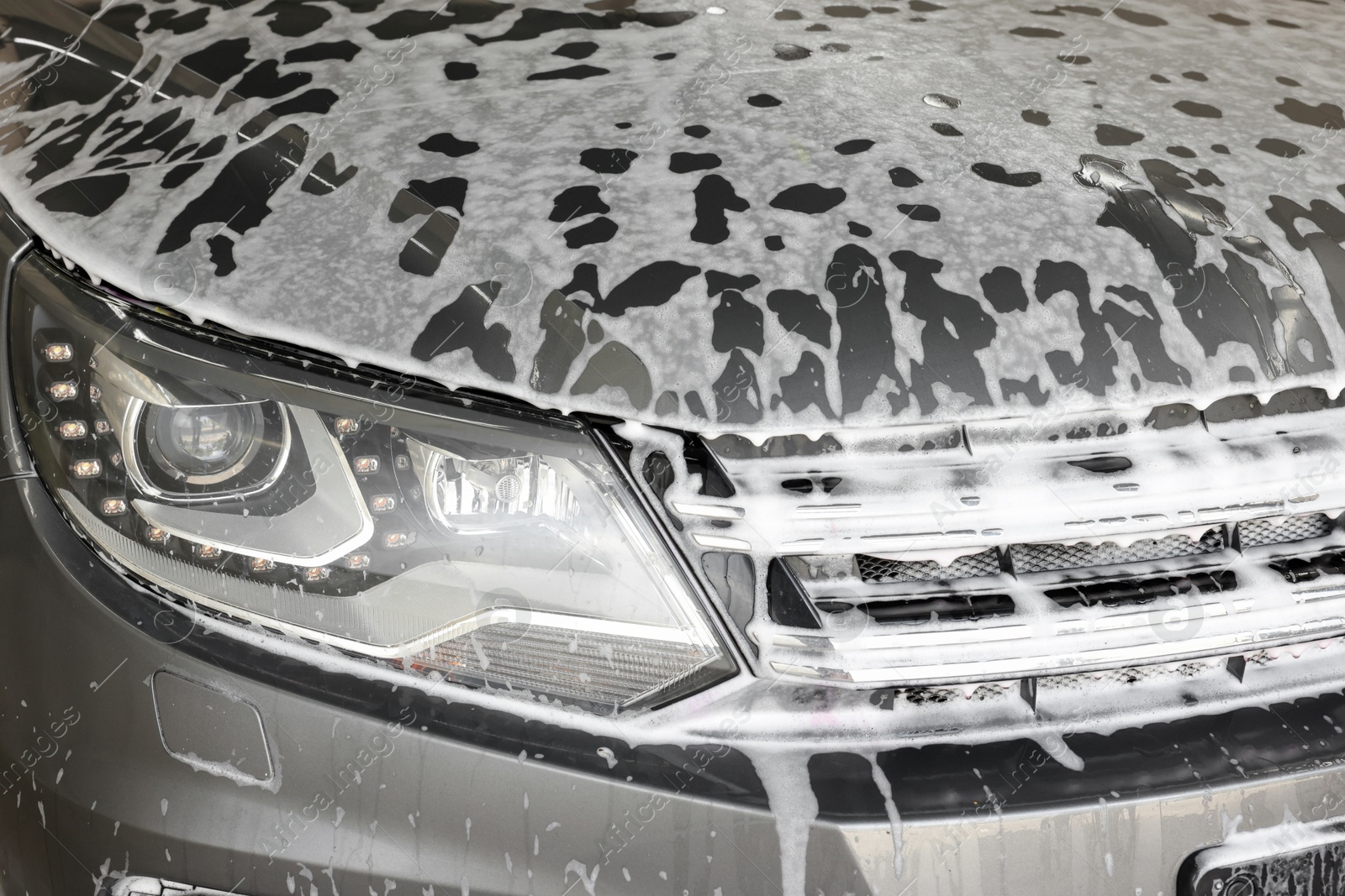 Photo of Auto covered with cleaning foam at car wash, closeup