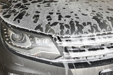 Auto covered with cleaning foam at car wash, closeup