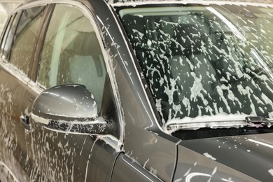 Photo of Auto covered with cleaning foam at car wash, closeup