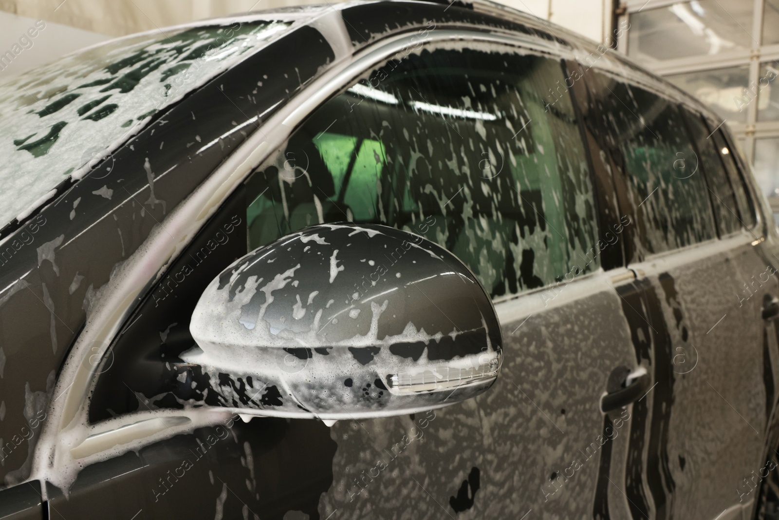 Photo of Auto covered with cleaning foam at car wash, closeup