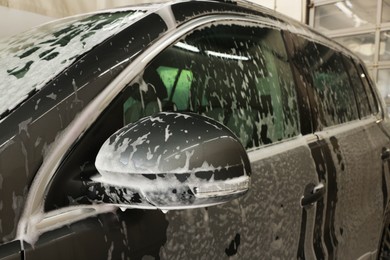 Photo of Auto covered with cleaning foam at car wash, closeup