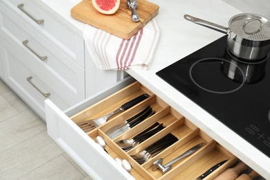 Photo of Box with cutlery in drawer, closeup. Kitchen utensils storage