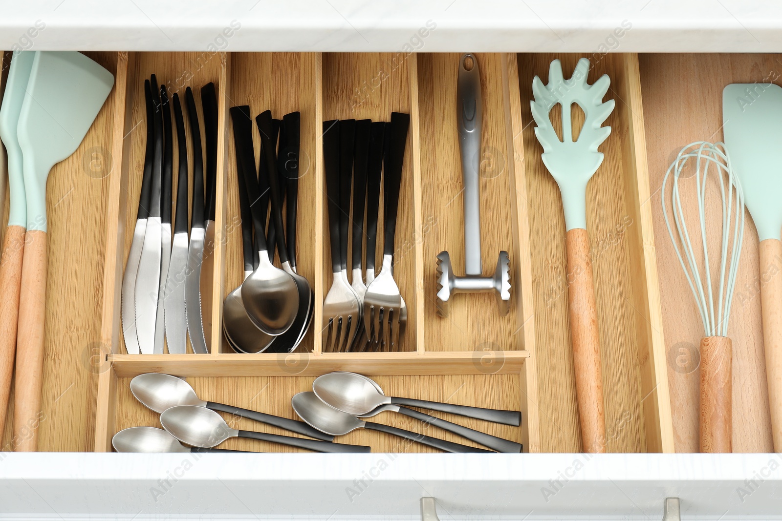 Photo of Cutlery in wooden box, closeup. Kitchen utensils storage