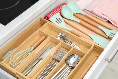 Photo of Box with cutlery in drawer, closeup. Kitchen utensils storage