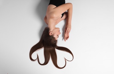 Beautiful young woman with hair in shape of hearts on white background, top view