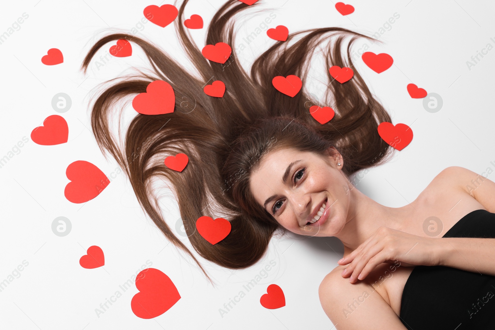 Photo of Beautiful young woman with long hair and red paper hearts on white background