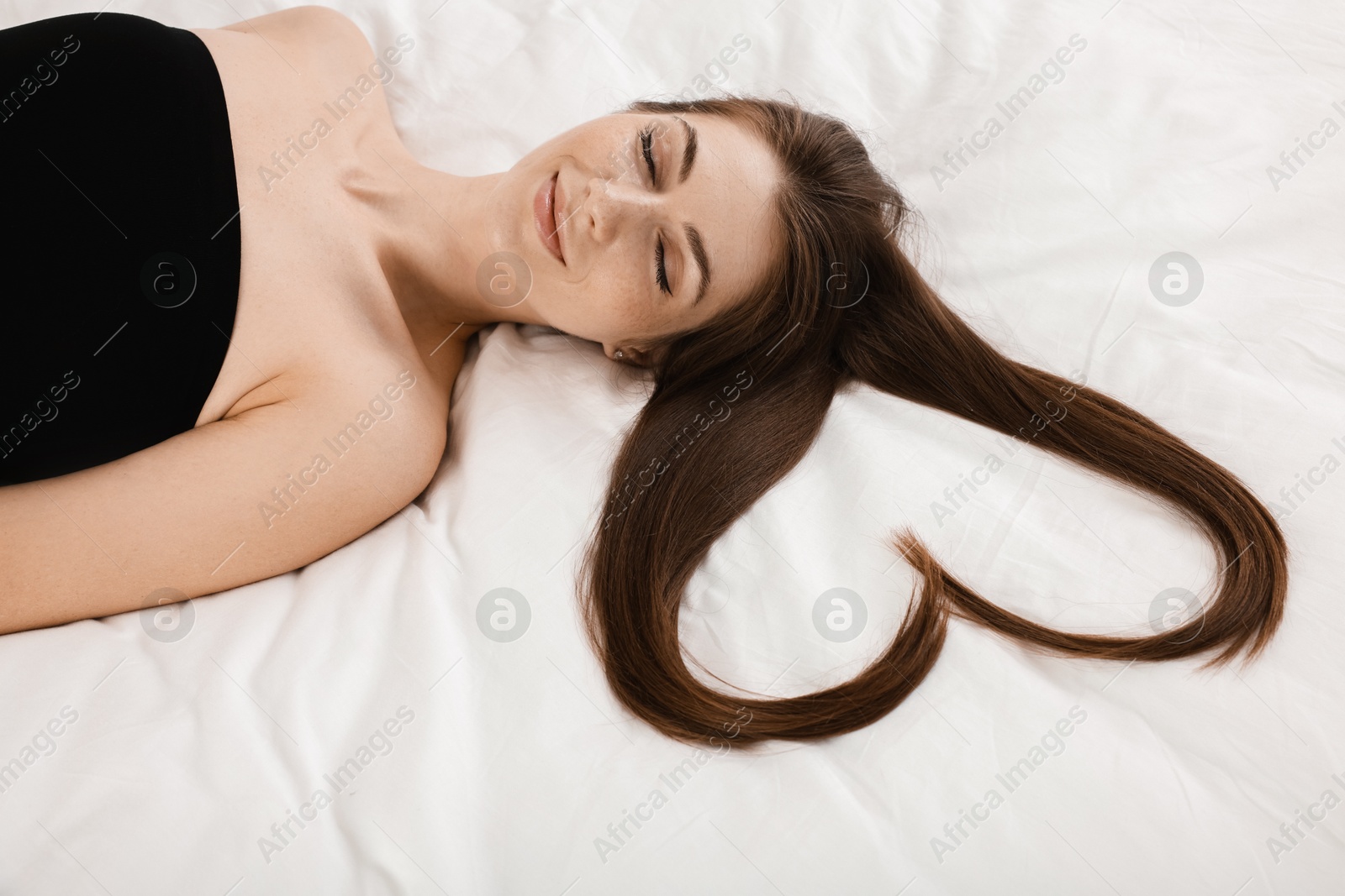 Photo of Beautiful young woman with hair in shape of heart on bed