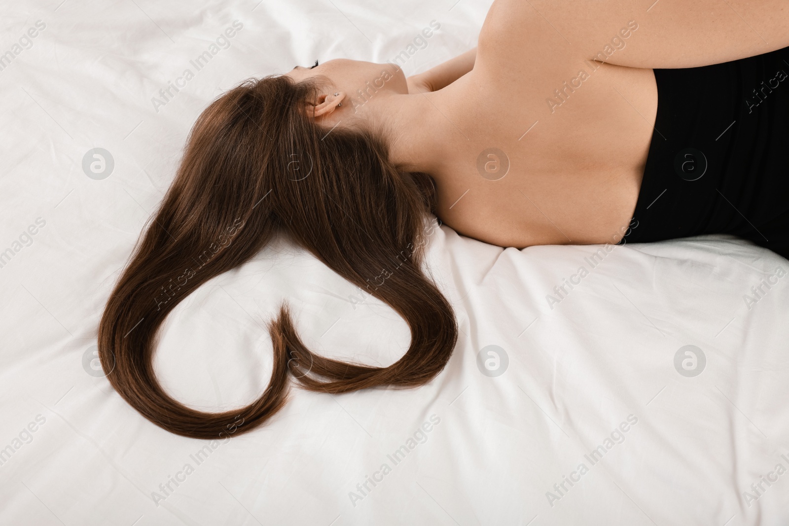 Photo of Young woman with beautiful hair in shape of heart on bed