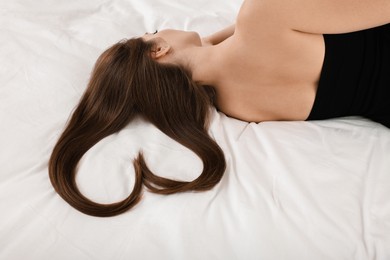 Photo of Young woman with beautiful hair in shape of heart on bed